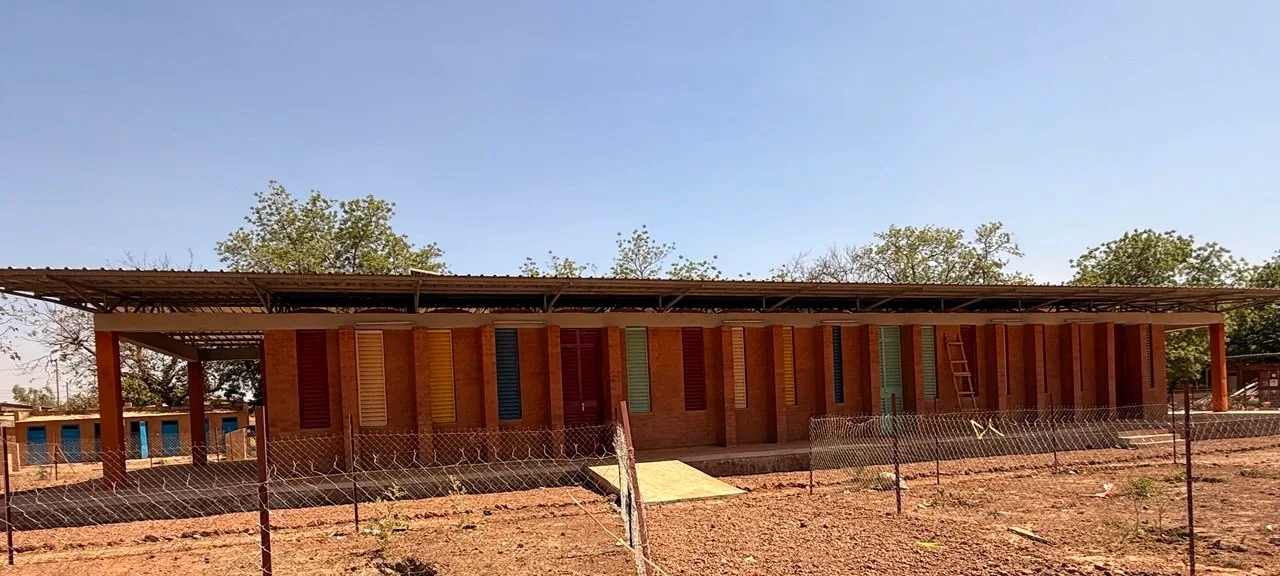 Vue laterale de l'ecole avec structure metallique et murs en terre compressee